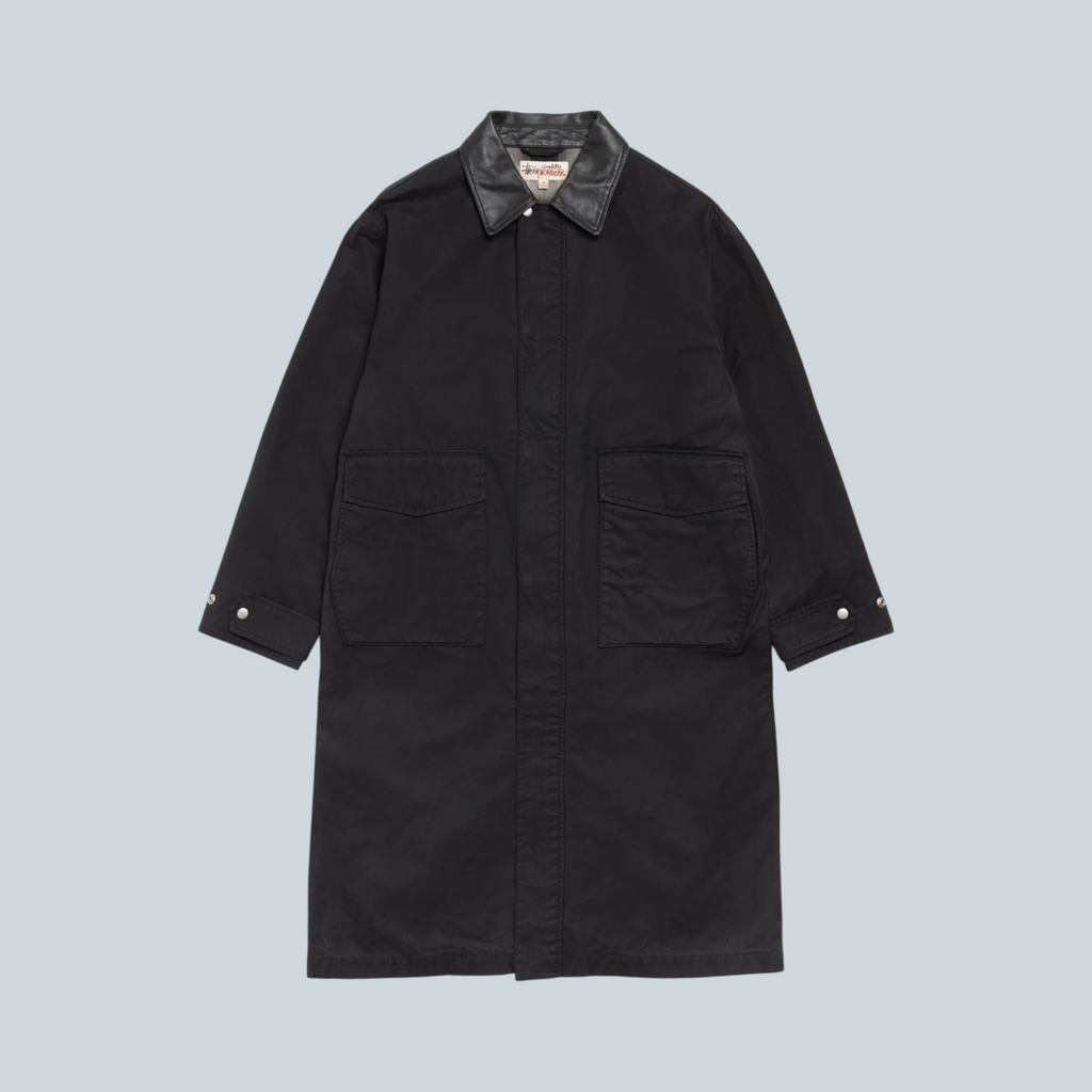 Manteau duster Stüssy noir en coton avec col contrastant et grandes poches avant, disponible chez Saison